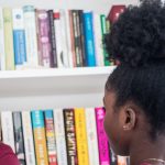 6 Must-Read Books to Celebrate Black History Month: Young Lady Standing in Front of a Bookshelf