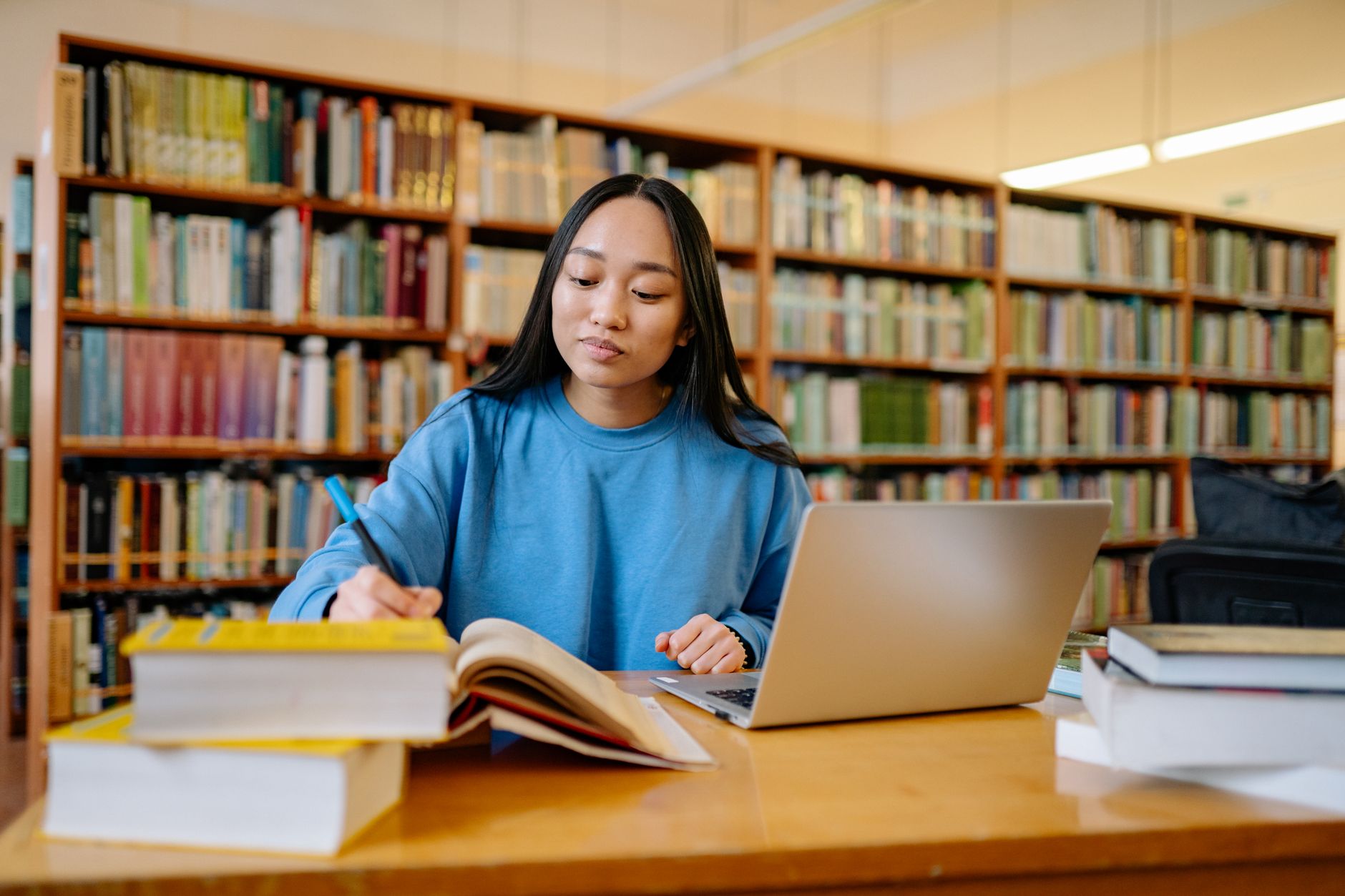 Student studying with books and a laptop while comparing course material options.